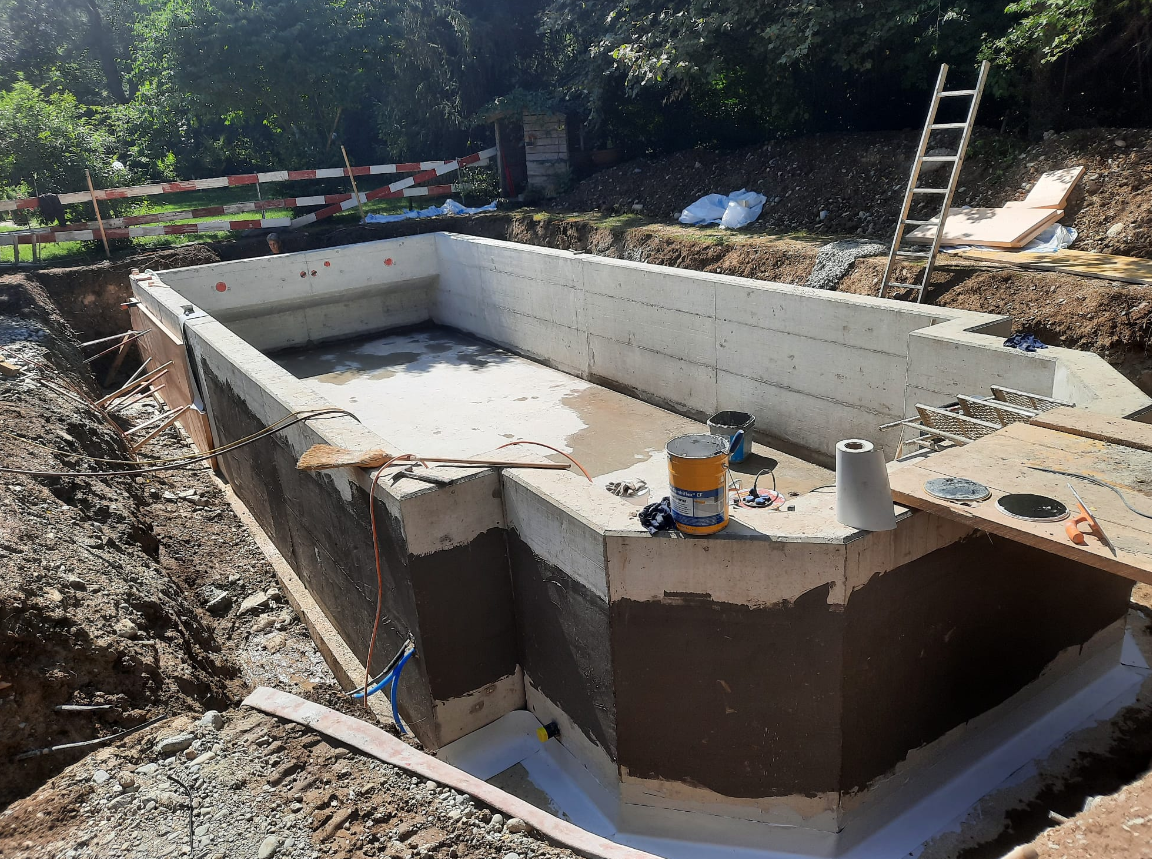 Fertig betoniertes Becken aus Sichtbeton im Garten, noch in der Baugrube