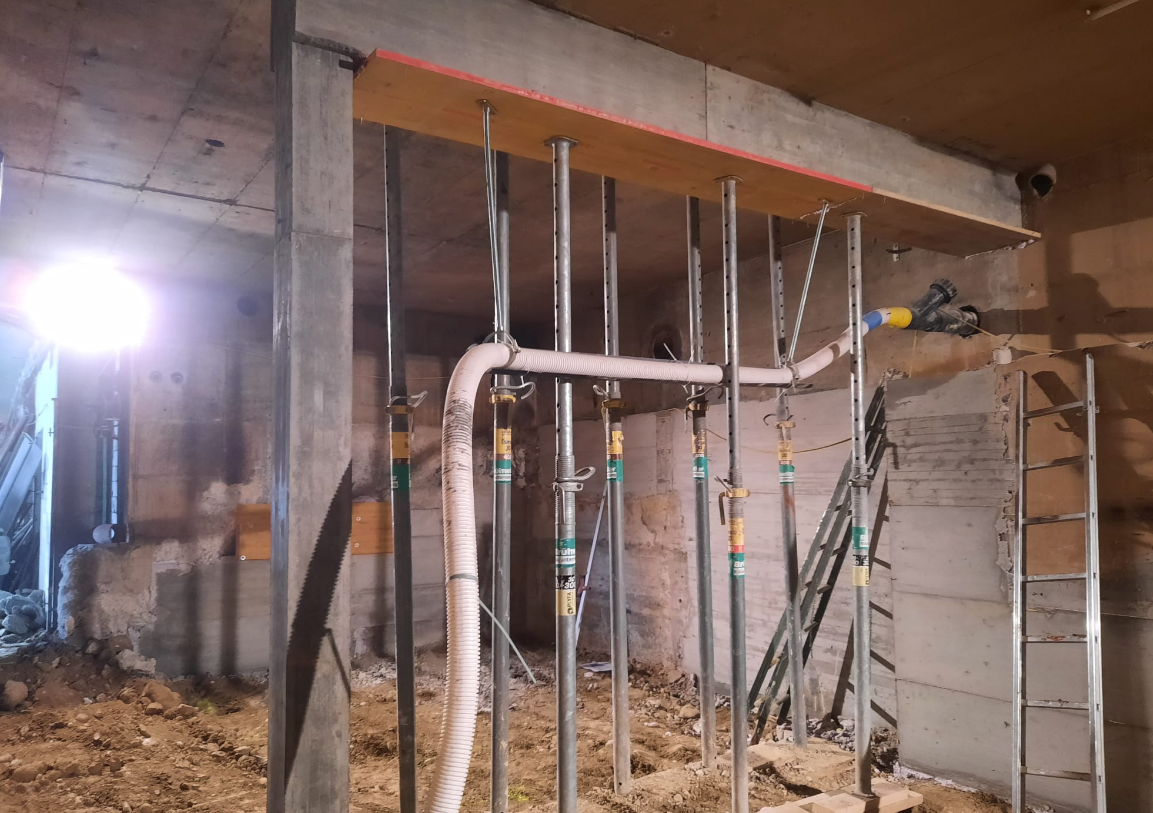 Abstützung einer Betondecke mit Baustützen im Untergeschoss während eines Umbaus